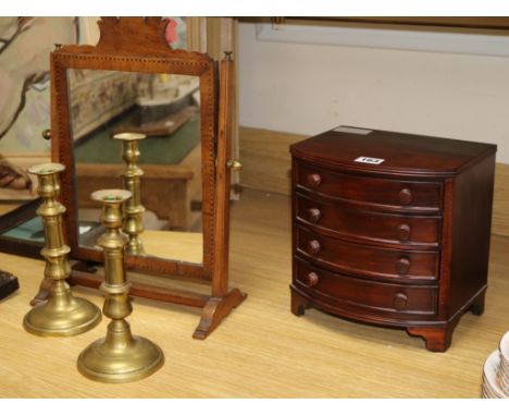 A mahogany toilet mirror, a pair of Victorian brass candlesticks and a miniature bowfronted chest of drawers (4)