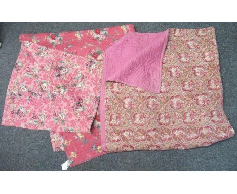 Two vintage cotton quilts, both pink ground; one reversible with different floral prints on either side and the other with a 