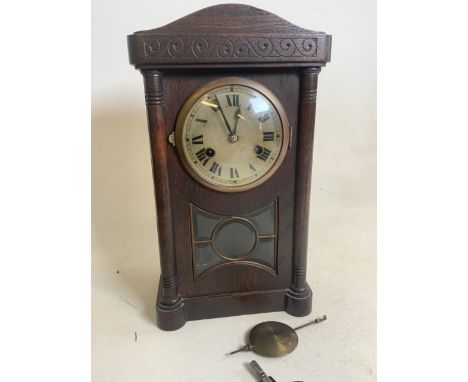 An early 20th century oak mantle clock with pendulum and key with bevelled glass five panel window.  W:22cm x D:14cm x H:37cm
