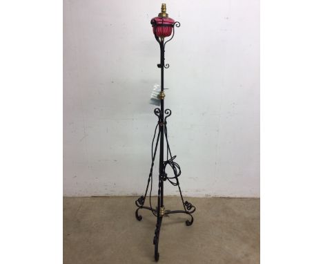 A wrought iron adjustable standard lamp with cranberry glass oil lamp - converted to electric - untested H:167cm to top of li
