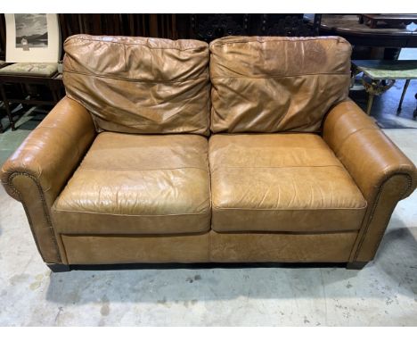 A two seater tan coloured leather sofa with stud detail to arms. W:155cm x D:100cm x H:85cm