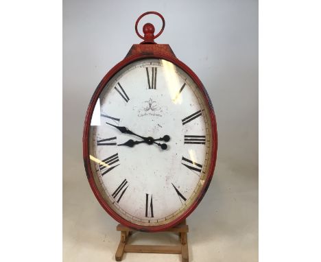 A large red metal oval shaped kitchen clock. Untested W:56cm x H:94cm
