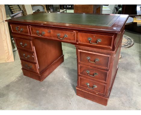 A reproduction leather topped pedestal desk with eight drawers with brass handles and two working keys, leather top in green 