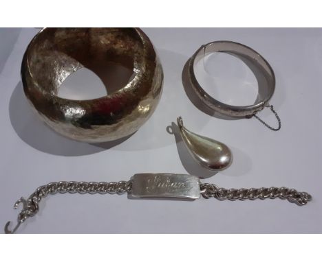 Four items of silver jewellery comprising a hammered metal bangle, a teardrop shaped pendant, an engraved hinged bangle with 