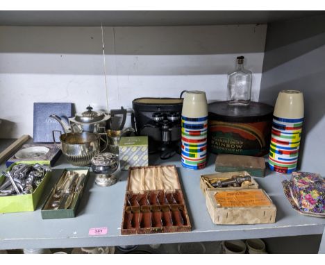 A mixed lot to include silver plate, vintage tins, window latches, binoculars, silver plated three-piece tea set, boxed cake 