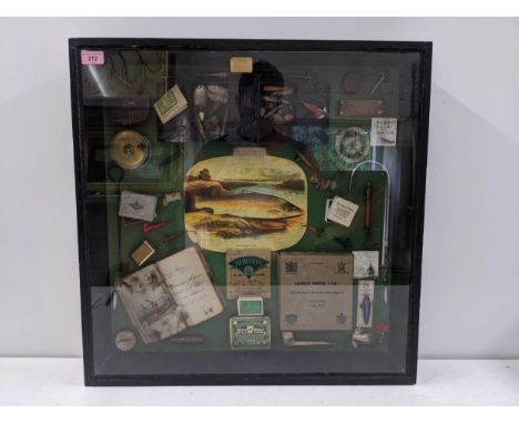 A glazed angling display case/collage displaying a pipe, cigarette boxes, floats, tackle scales and other items 64cm h x 80cm