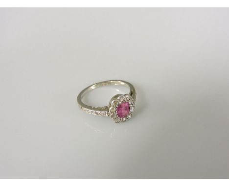 An Art Deco ruby and diamond oval cluster ring, with diamond set shoulders, marked 18ct