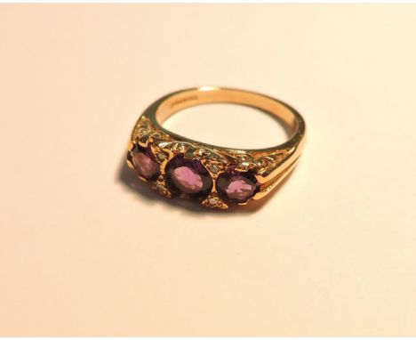 A 9ct gold three stone amethyst carved head style ring, with pairs of diamond set points, and a 9ct gold diamond and emerald 