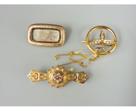 A Victorian 9ct gold ruby and split pearl bar brooch, a Georgian gold memorial brooch with snakeskin effect border, and an Ed