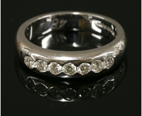 An 18ct white gold diamond set band ring, with seven brilliant cut diamonds rub set to the head, finger size N