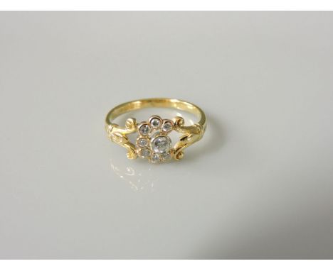 An 18ct gold diamond cluster ring, with fleur de lys shoulders