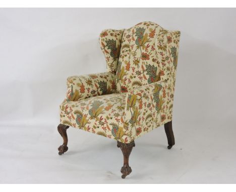 A wing back armchair, recently reupholstered in print fabric, on claw and ball feet