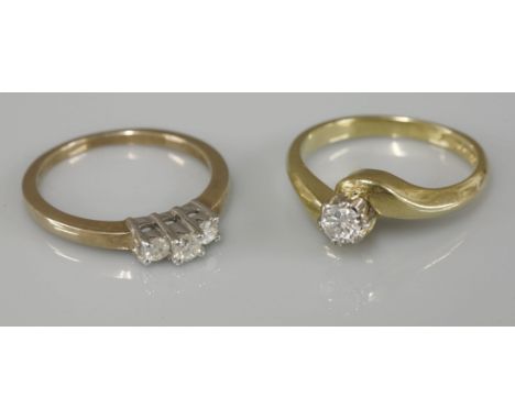 An 18ct gold single stone diamond crossover ring, and a 9ct gold three stone diamond ring