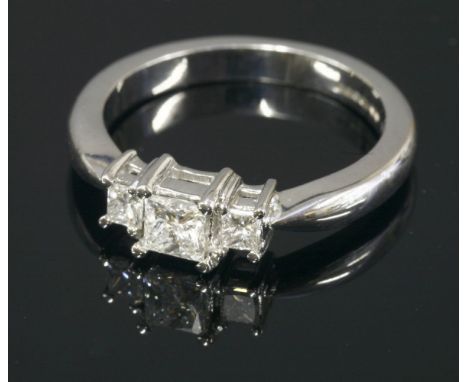 An 18ct white gold three stone diamond ring, with three graduated princess cut diamonds claw set to plain collets, solid knif