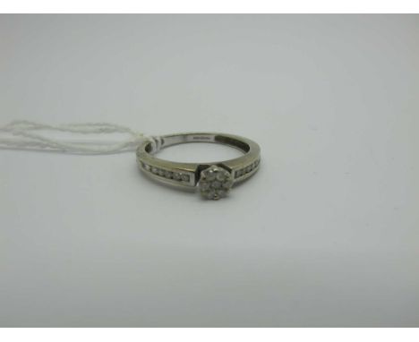 A Modern 9ct White Gold Diamond Cluster Ring, claw set to the centre, between channel set shoulders, stamped ".25" (finger si