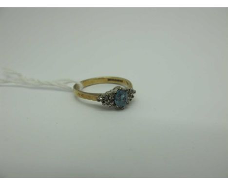 A Modern 9ct Gold Blue Topaz and Diamond Dress Ring, oval claw set to the centre, between diamond set shoulders (finger size 