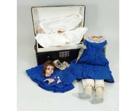 A poured wax shoulder head doll with trunk and clothing, English circa 1860, with blue glass eyes, (one loose), painted mouth