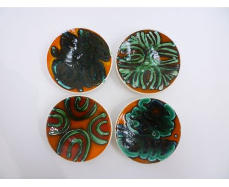 Four Poole Delphis pin dishes in orange, green and black colourways, black back stamps to three, one blue, 12.5cm diameter 