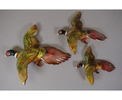 Three vintage flying duck wall figurines the medium sized with repair to wing, 25cm wide (largest)