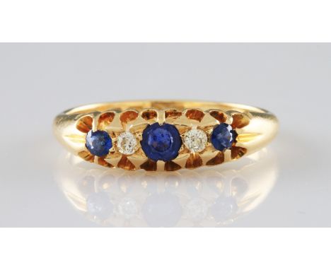 An 18ct yellow gold sapphire and diamond five stone ring, set centrally with a round cut sapphire, flanked to either side wit