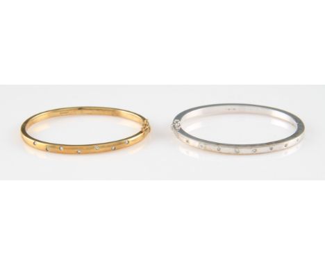 A white metal diamond set hinged bangle, half of the bangle flush set with ten evenly spaced round brilliant cut diamonds, ap