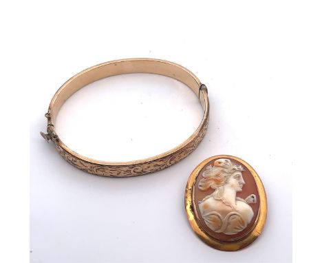 A shell cameo brooch depicting a lady in profile, stamped 9ct. Length 37mm. Weight 5.48g.  And a 9ct metal core hinged bangle