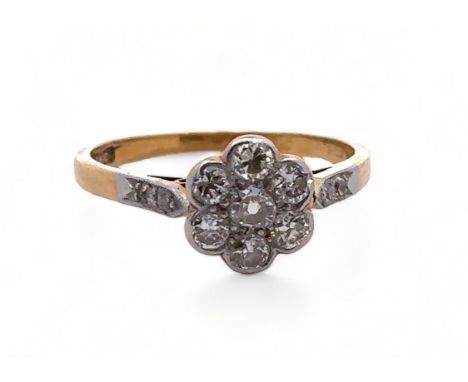 An 18ct gold and diamond flower head cluster ring. Seven brilliant cut diamonds, the central diamond with large culet. Total 