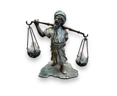 Interesting cold painted bronze figure of a water carrying man, with two glass orbs attached to frame by chains. Unmarked to 