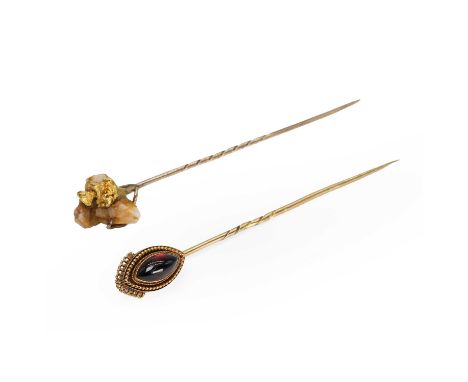 A garnet stick pin and a gold nugget specimen stick pin, the garnet stick pin with a navette shaped garnet cabochon, bezel se
