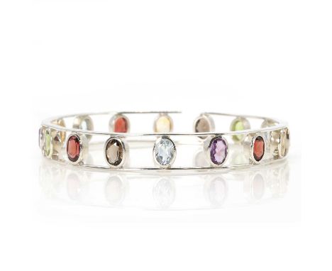 A silver vari-coloured gemstone bangle, with oval cut gemstones, comprising amethyst, aquamarine, citrine, garnet, peridot an