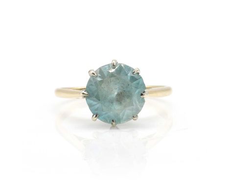 A blue zircon single stone ring,  with a round cut blue zircon, 9mm in diameter, claw set in white to a yellow under bezel, i