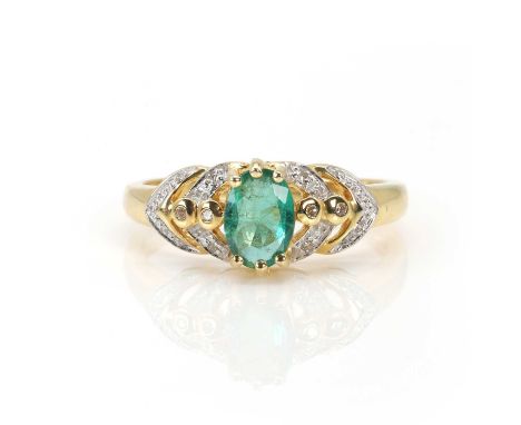 An 18ct gold emerald and diamond ring,  with an oval cut emerald, 7mm x 5mm, six claw set into pierced shoulders bezel and gr