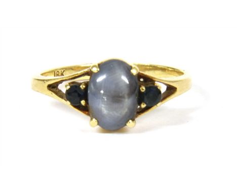 A sapphire ring, with an oval cabochon star sapphire, four claw set to the centre, with a round cut sapphire at each side, to