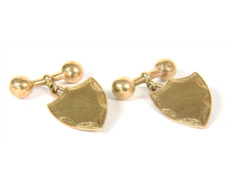 A pair of gold cufflinks, flat shield shaped heads with scrolling hand engraved border, chain fitting to hollow barbell back,