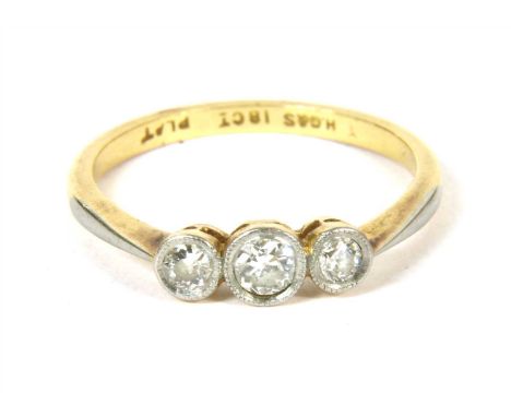 A gold three stone diamond ring, three Swiss cut diamonds, rub set to white setting plates, to a yellow chenier gallery and p