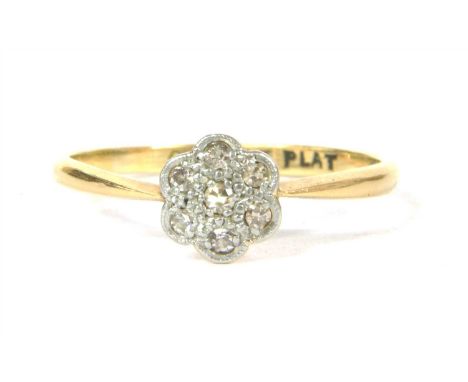 A gold diamond daisy cluster ring, seven single cut diamonds, grain set to a white setting plate, with yellow gallery and pla