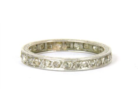 A diamond eternity ring, with single cut diamonds grain set to hand engraved guards, tested as platinum, size approximately M