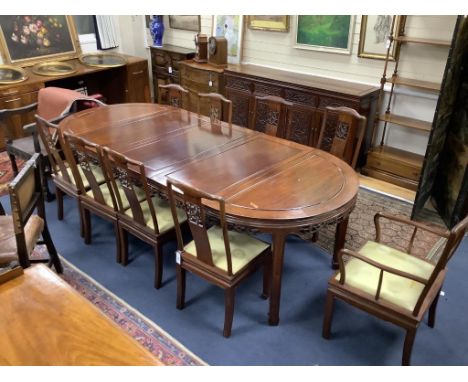 A 20th century Chinese carved hardwood dining room suite comprising sideboard fitted with four drawers above four carved pane