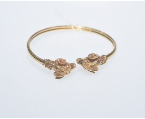 A Greek 18ct gold bangle, with rams head terminals and stamped marks. 24.8gms