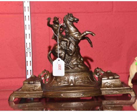 A late 19th century spelter desk standish cast with the mounted figure of a hunter with whip and gun above a well flanked by 