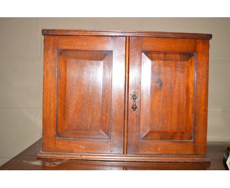 A small mahogany wall hanging cupboard, with two fielded panel doors enclosing a single shelf.