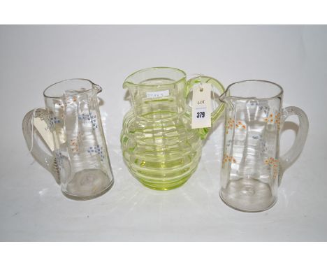 A pair of Victorian glass water jugs with hand-painted enamel floral decoration; and a green tinted glass jug.