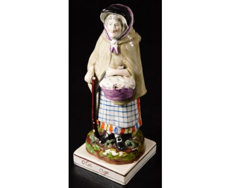 An early 19thC Staffordshire pottery figure Old Age, the female figure with walking stick and basket, on a square base, c1810