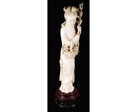 A Japanese Taisho period ivory figure, of a lady in flowing robes holding basket and flowers, on a pierced wooden base, 28cm 