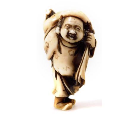 A Japanese Meiji period carved and stained ivory netsuke, formed as a man in standing pose holding sack of his shoulder, mark