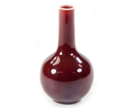 A Chinese porcelain sang de boeuf bottle vase, in deep red, with cylindrical stem and bulbous body, on circular foot, blue se