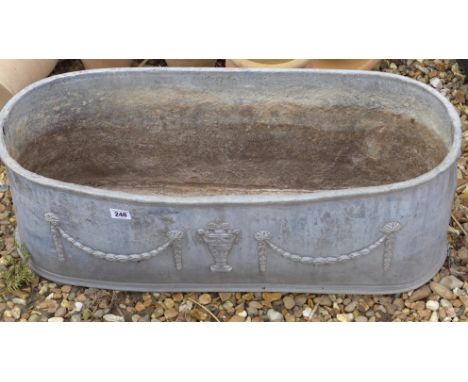 An antique lead oval planter with raised urn and garland decoration - Width 77cm