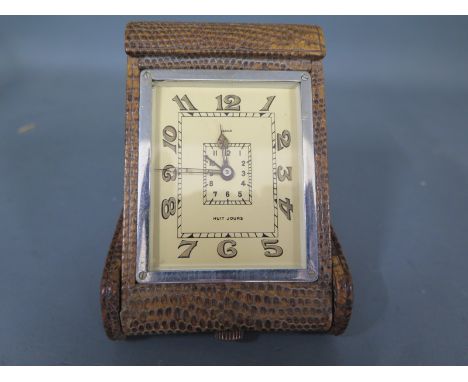 A Jaeger travelling alarm clock in a faux snakeskin cover - in working order