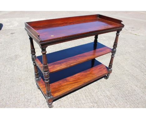 A mahogany three-tier buffet table with raised back and sides, on turned, shaped and castored supports, 45” wide x 19 1/4” de