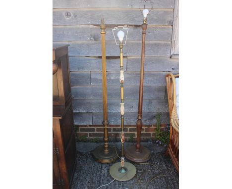 A brass and turned onyx standard lamp, a giltwood and fluted standard lamp, and a&nbsp;walnut standard lamp, on circular base